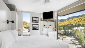Ein modernes Hotelzimmer mit einem großen Bett, einem Flachbildfernseher und Bergblick.
