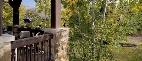 A covered outdoor area with stone walls, a wooden deck, and a grill.