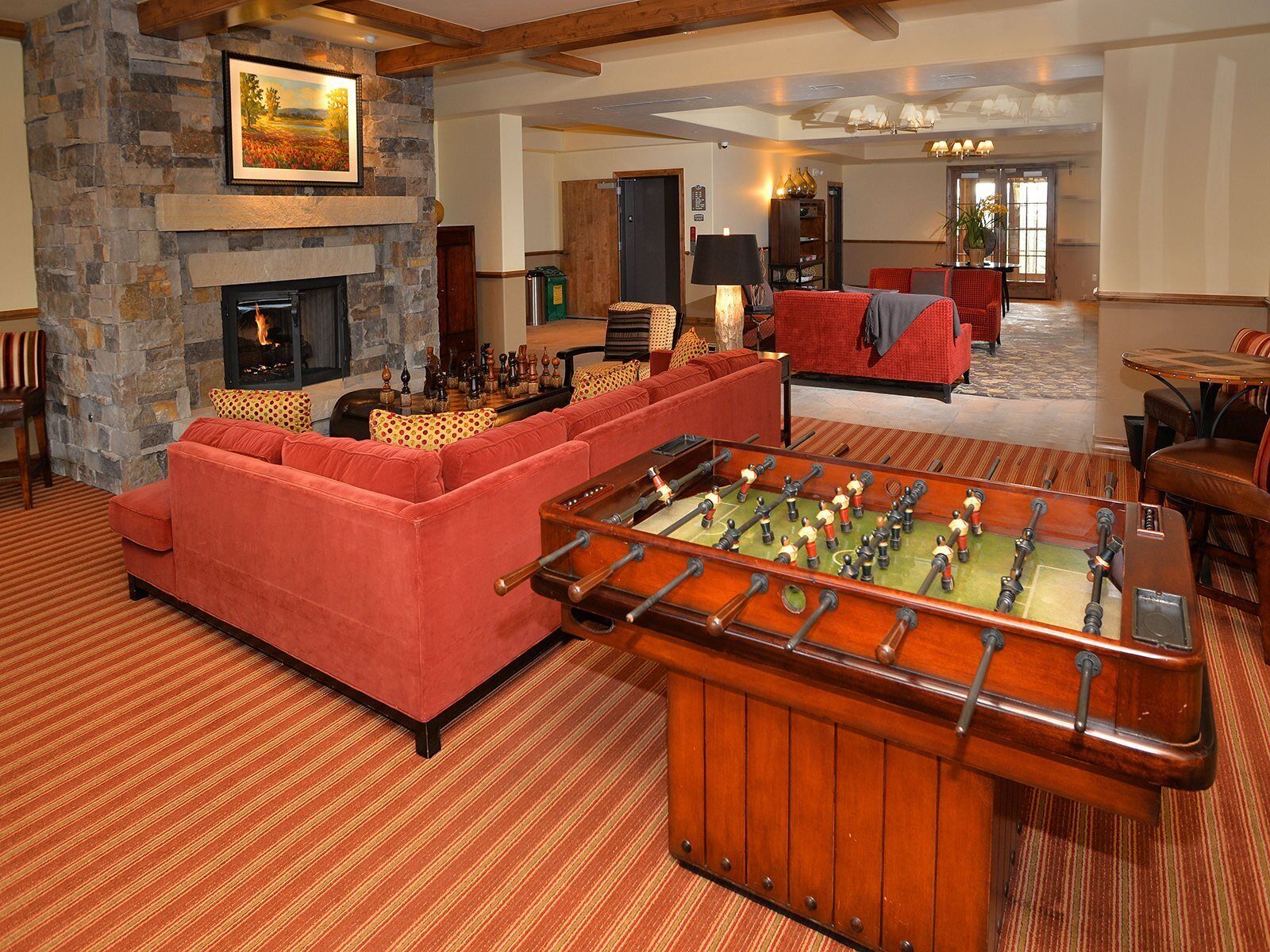 A cozy living room with a stone fireplace, a red sofa, and a foosball table.