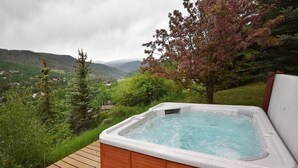 A hot tub on a wooden deck with a view of a mountainous landscape. - Glacier Court 1844 B (Vail)