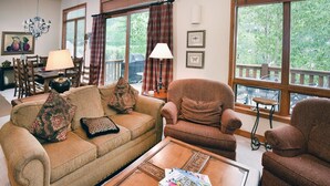 A cozy living room with a sofa, armchairs, a coffee table, and a dining area with chairs and a table. - Glacier Court 1844 B (Vail)
