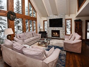 A spacious living room with a stone fireplace, large windows, and a cozy seating area.