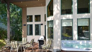 An outdoor patio with a hot tub, chairs, and a grill. - Meadow Brook Chalet (Vail)