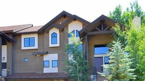 A two-story house with a stone foundation, a garage, and a staircase leading to the entrance. - Meadow Brook Chalet (Vail)