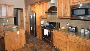 A kitchen with wooden cabinets, a stainless steel refrigerator, a stove, and a microwave. - Meadow Brook Chalet (Vail)