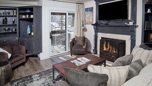 Un salon chaleureux avec une cheminée, un canapé, une table basse et une bibliothèque.