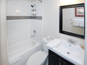 A modern bathroom with a bathtub, toilet, sink, and a shower with a towel rack.
