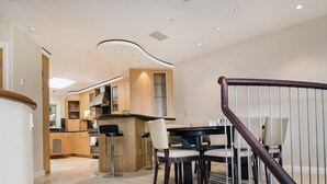 A modern kitchen with wooden cabinets, a central island, and a dining area with a round table and chairs.