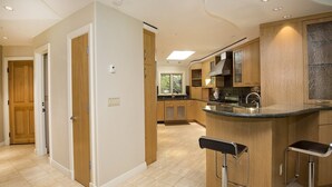 A modern kitchen with a central island, wooden cabinets, and a view to the outside.