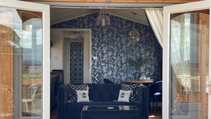 Una sala de estar acogedora con un sofá azul oscuro, una mesa de centro de vidrio y un tapete estampado.