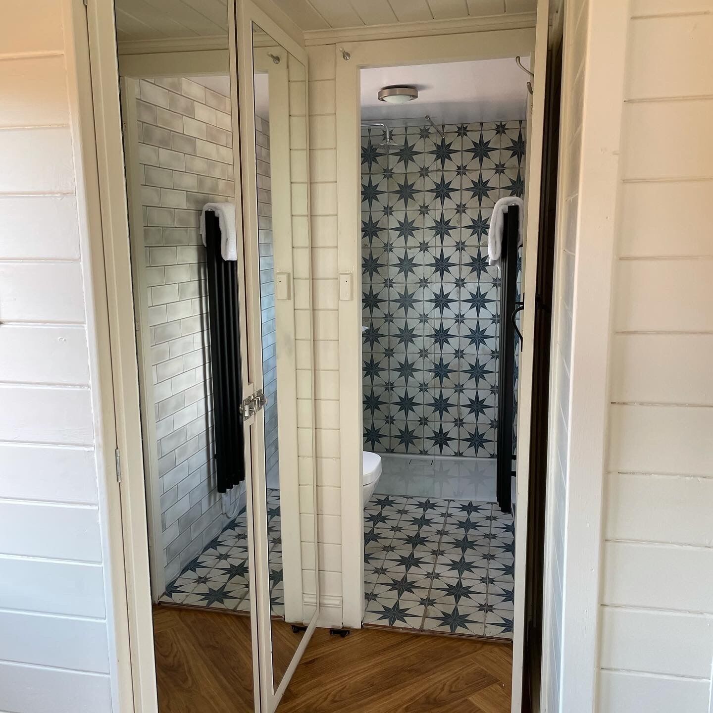 A bathroom with a shower, toilet, and a patterned floor.