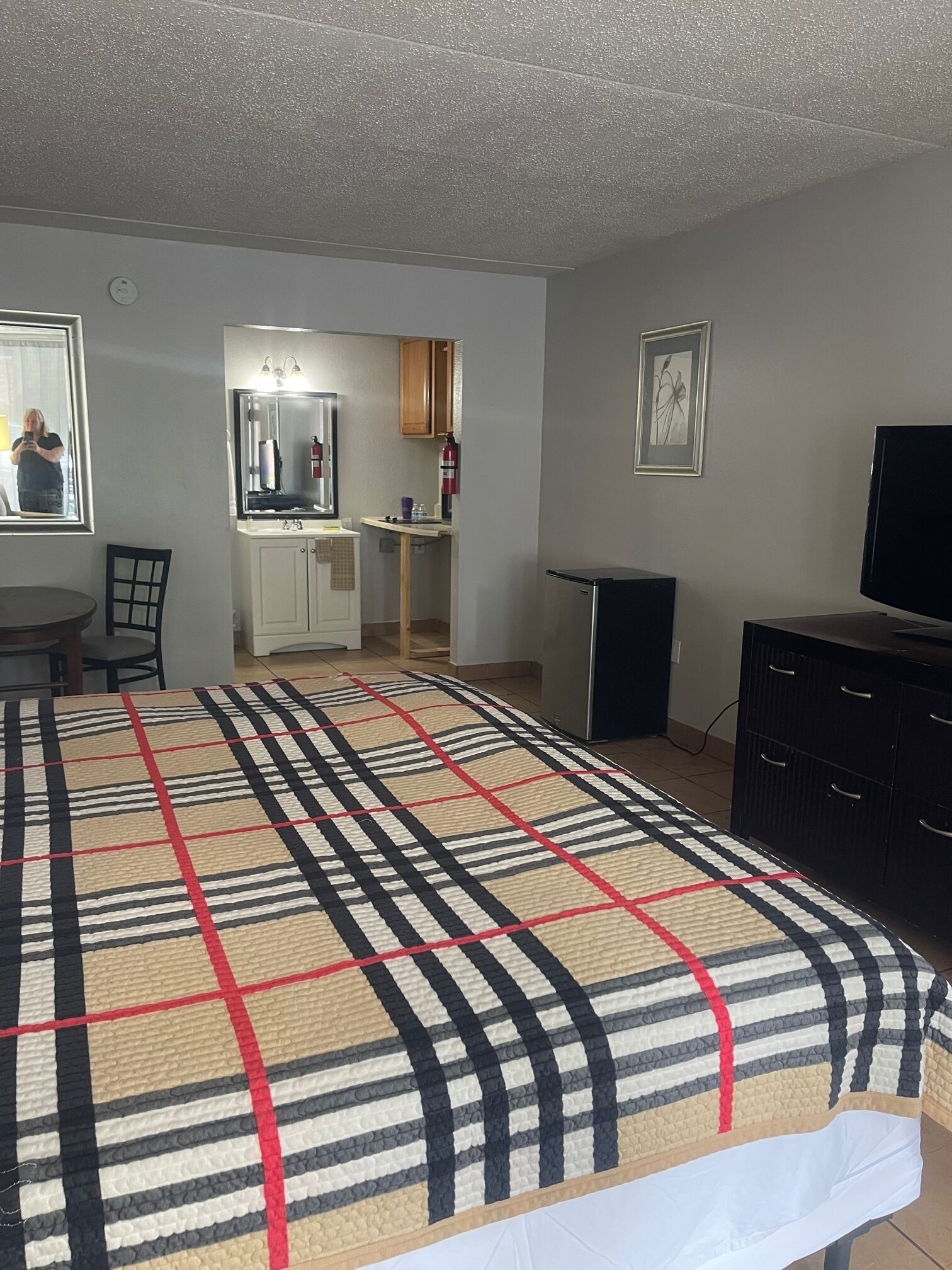 A hotel room with a bed, a TV, a desk, and a mirror.
