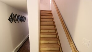 Un escalier en bois avec une rampe en bois et un interrupteur fixé au mur.