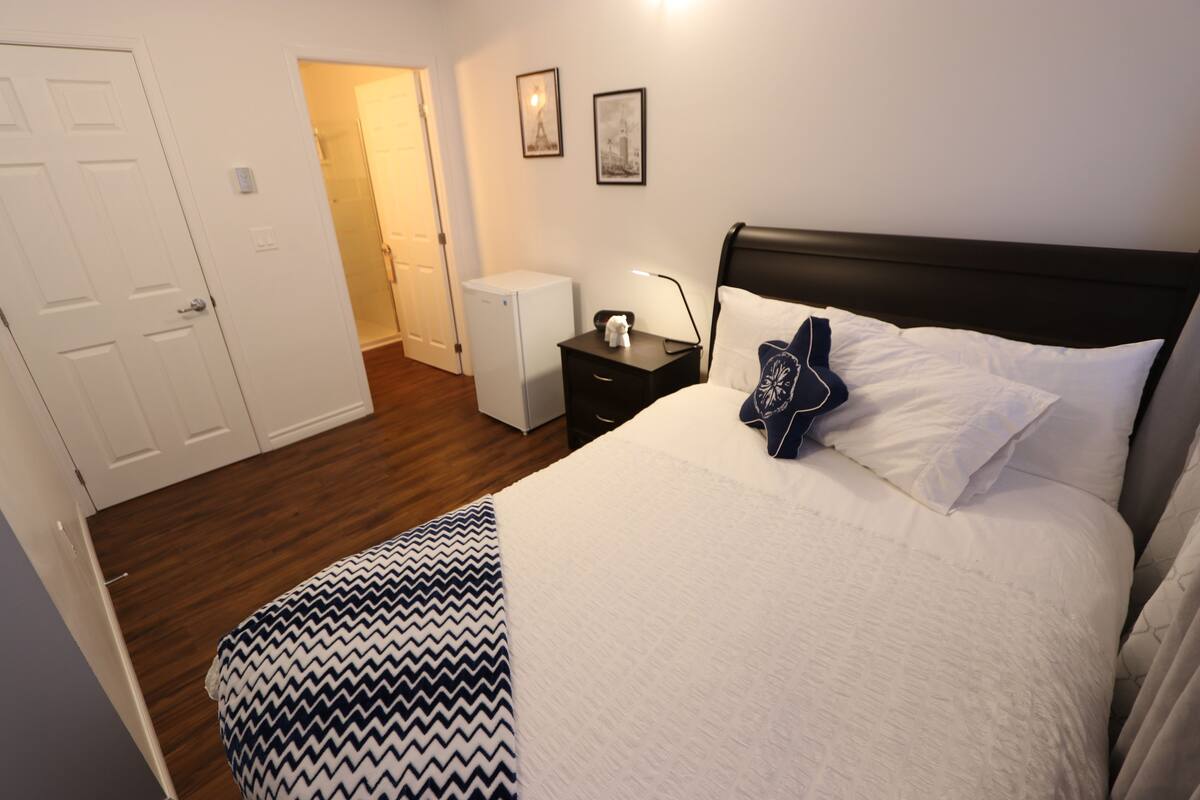 A hotel room with a bed, a nightstand, a lamp, and a white door.