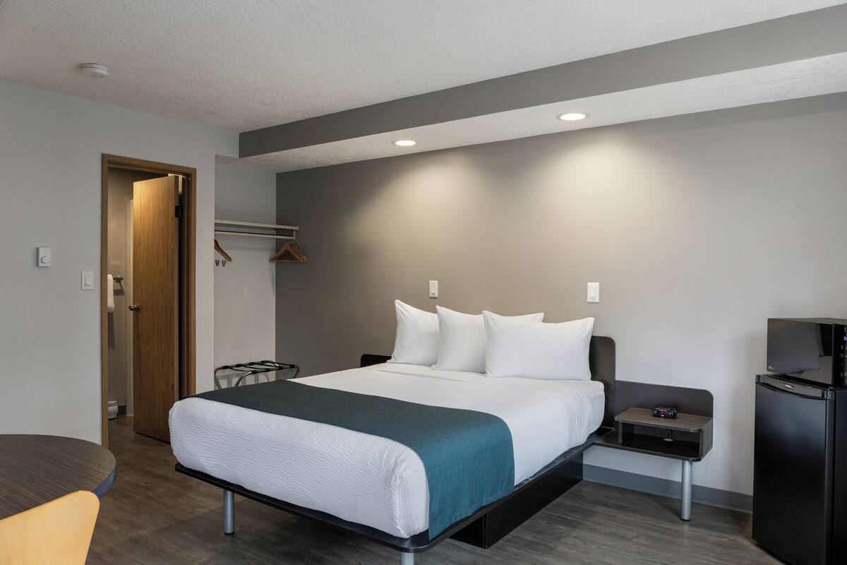 Une chambre d’hôtel moderne équipée d’un lit, d’une table de chevet, d’une télévision et d’une armoire.