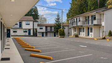 A motel with a row of parking spaces, a covered walkway, and a building with multiple floors and balconies.