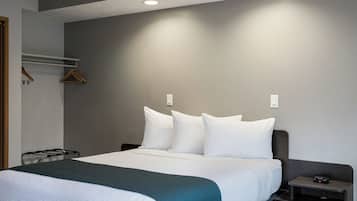 A hotel room with a bed, bedside table, and a wall-mounted coat rack.