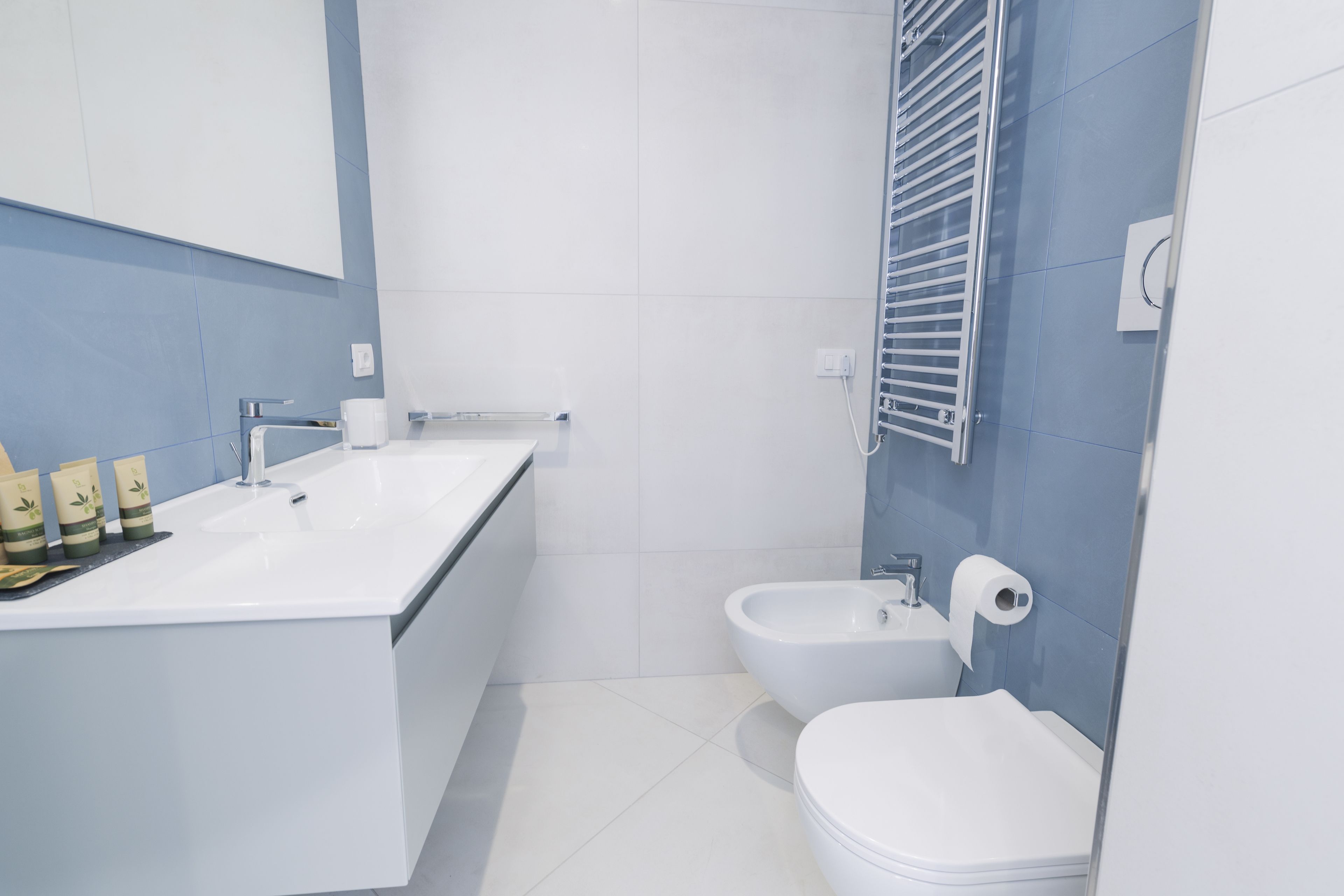 A modern bathroom with a white sink, a bidet, and a toilet.