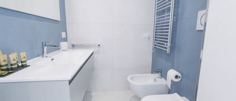 A modern bathroom with a white sink, a bidet, and a toilet.