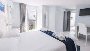 A hotel room with a large bed, a desk, and a chair. There is a balcony with curtains. - Relais Kaora (Sant'Agnello)
