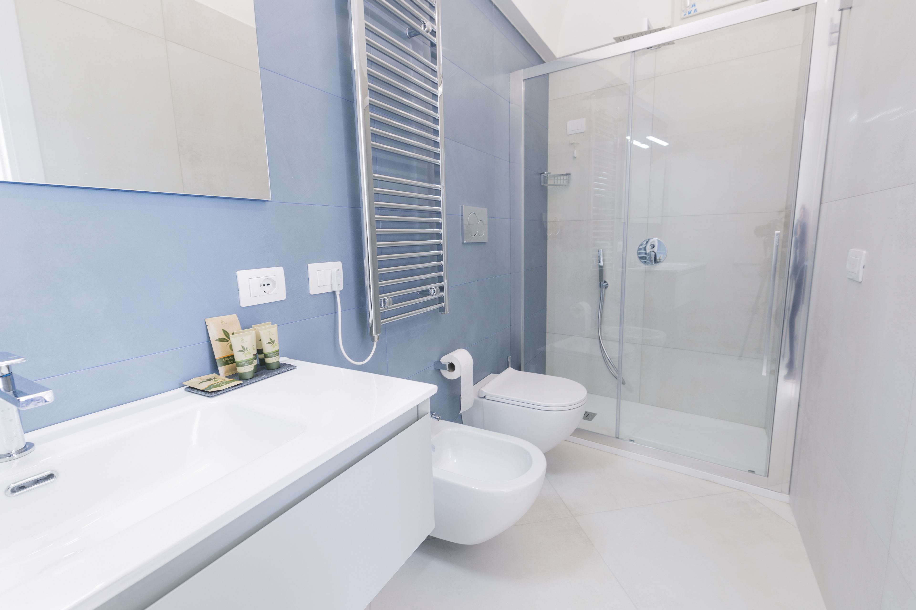A modern bathroom with a white sink, a bidet, and a glass-enclosed shower.