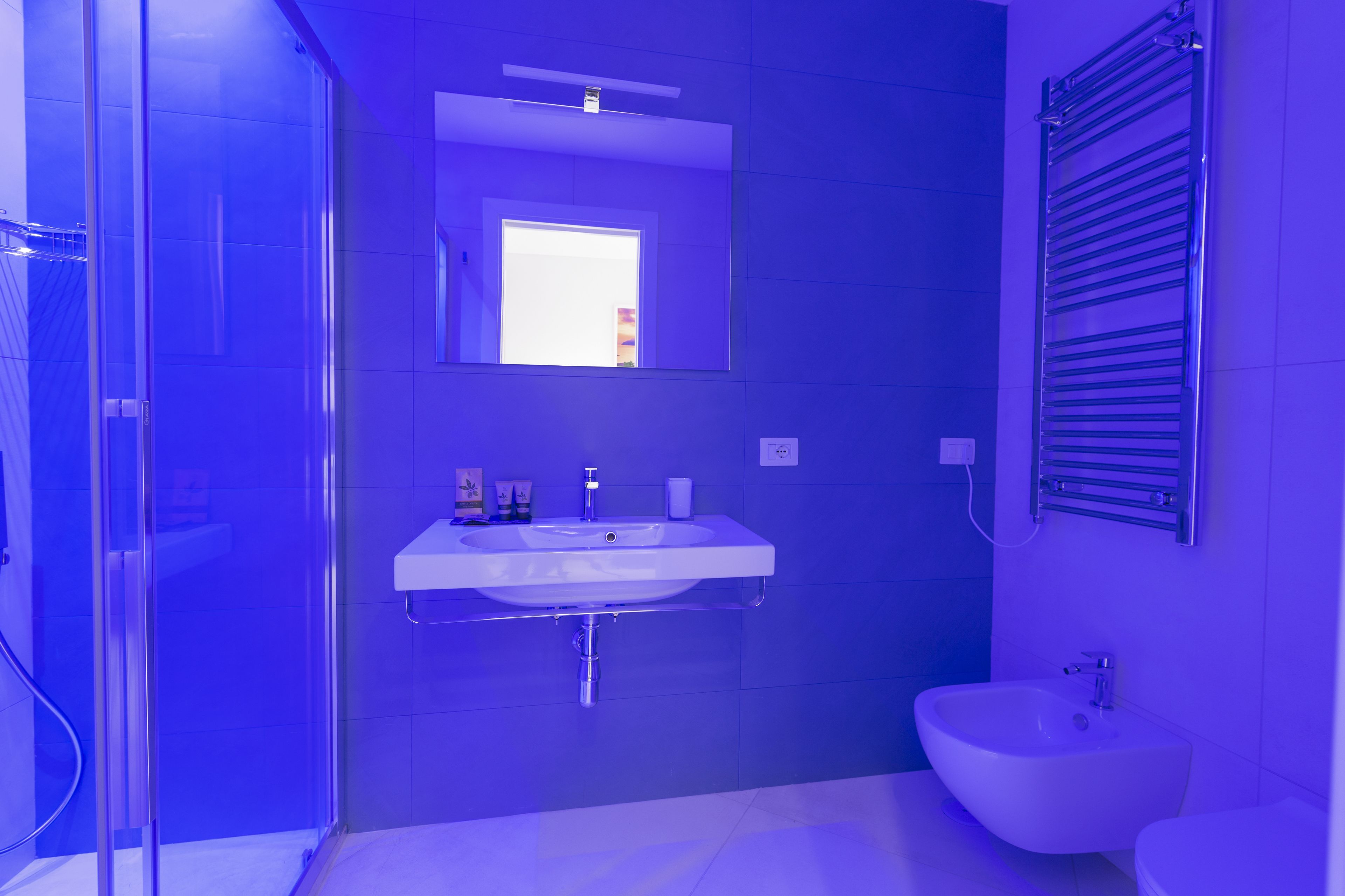 Un baño moderno con cabina de ducha de vidrio, un lavabo blanco con espejo y un bidé.