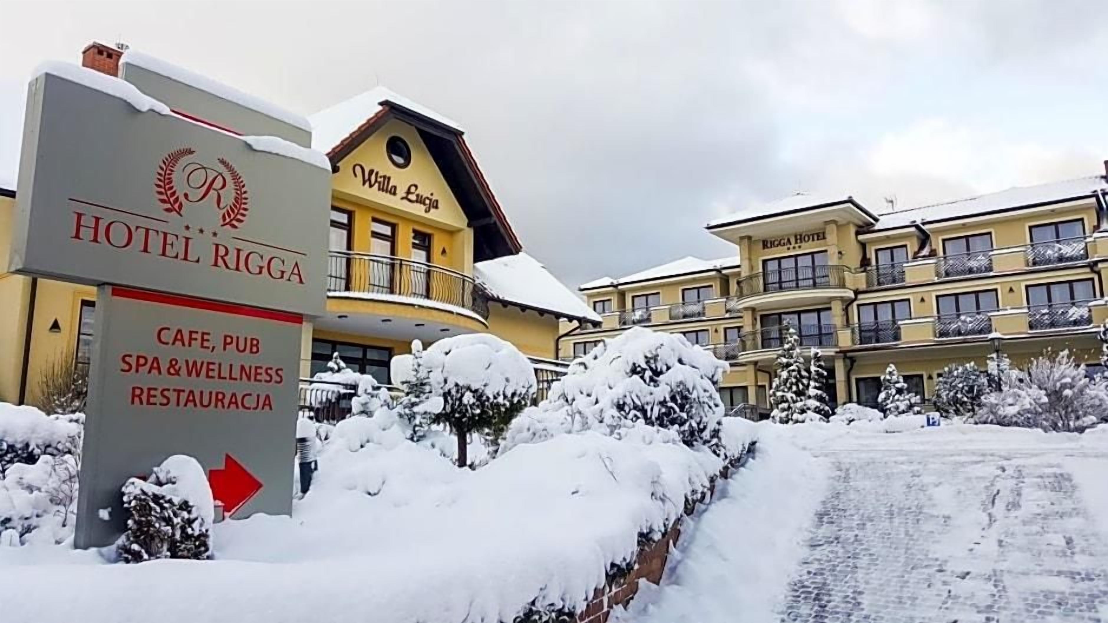 A hotel entrance with a sign for Hotel Rigga, indicating a cafe, pub, spa, wellness, and restaurant.