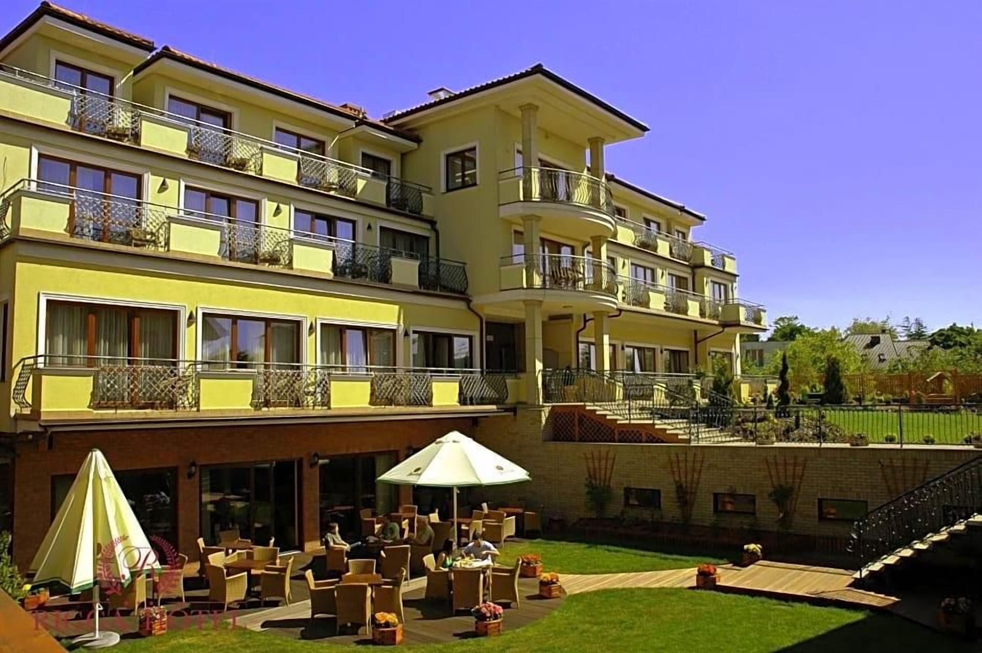 A multi-story hotel with outdoor seating and a well-maintained lawn.