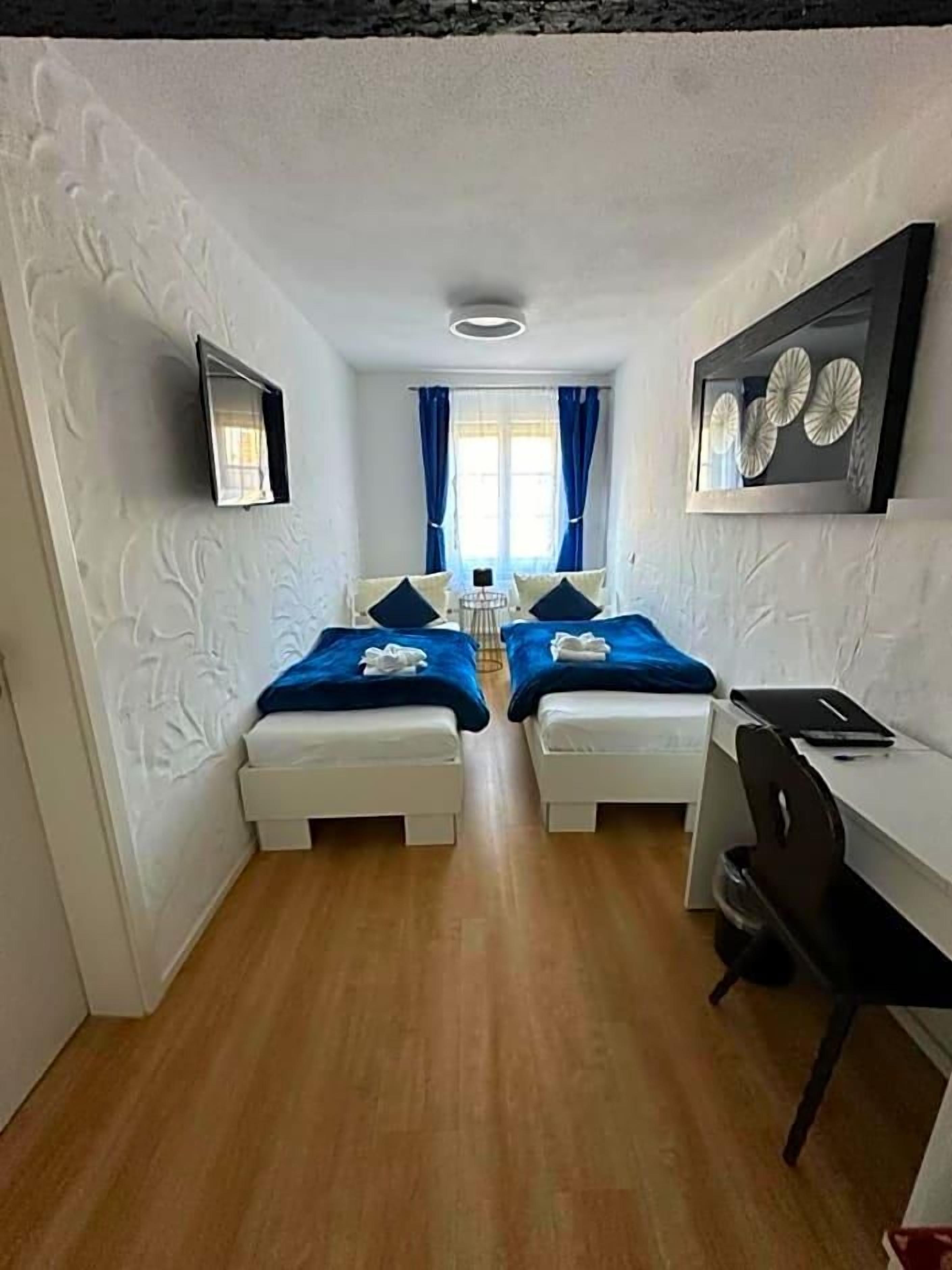 A room with two beds, a desk, and a chair.
