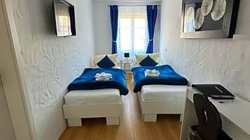 A room with two beds, a desk, and a chair.