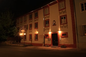 Un edificio con varias ventanas y una puerta, iluminado por luces exteriores.