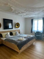 Un dormitorio con una cama de madera, un espejo grande y una ventana con cortinas.