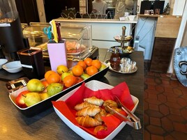 Un bufé de desayuno con frutas, bollería y salsas.