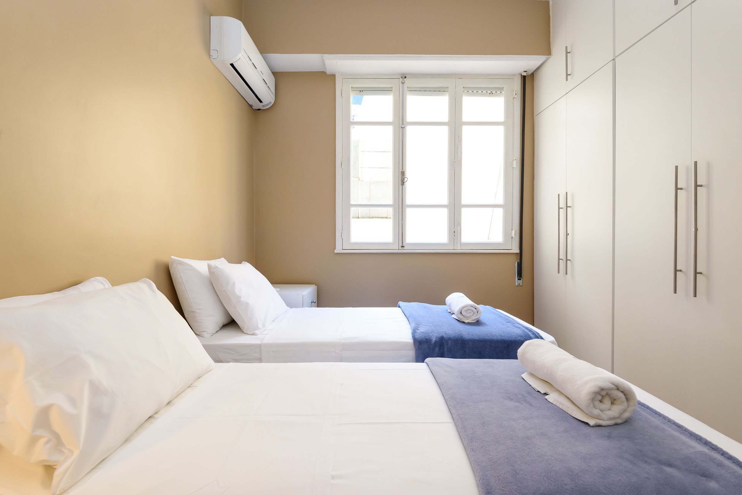 Une chambre d’hôtel avec deux lits, une fenêtre et une armoire.