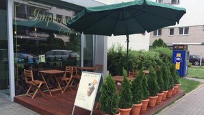A café with outdoor seating, a green umbrella, and a signboard.