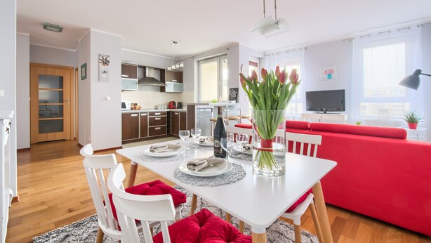 A modern living room with a dining area, red sofa, and a TV.