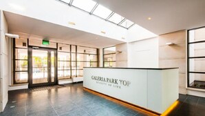 Modernilla designilla sisustettu vastaanottoaula, jossa on vastaanottotiski, jonka kyltissä lukee ”GALERIA PARK TOP” ja ”ELÄMÄNLAATU”.