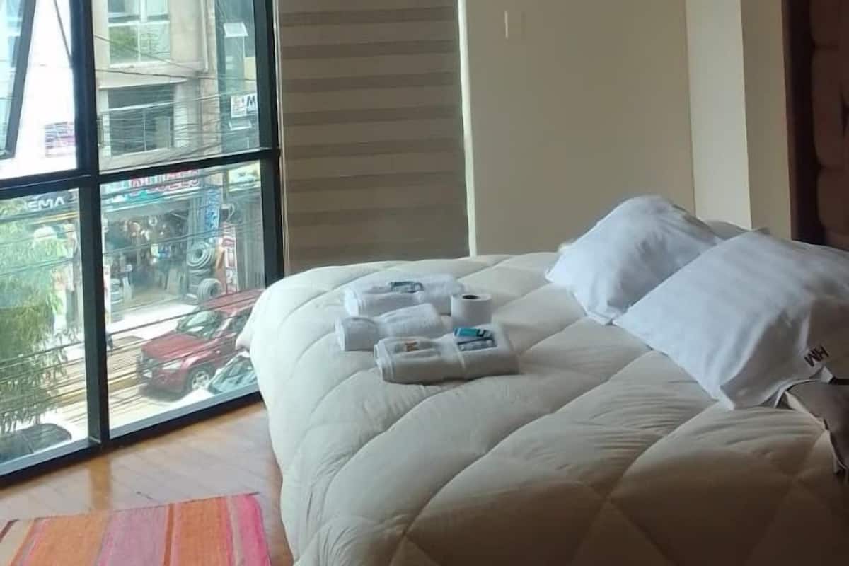 Ett hotellrum med en stor säng, utsikt genom en skjutdörr och en randig matta.