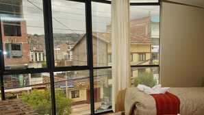 Una habitación de hotel con un ventanal grande, una cama, una mesa y una alfombra.