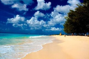 A beach with clear blue water, sandy shore, and a few people. - Valersk Vacation Apartments (Oistins)