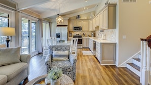 A spacious kitchen with modern appliances, a dining area with patterned furniture, and a cozy seating area with a sofa and cushions. - Charming Ocean view Retreat! Newly Remodeled (Hilton Head Island)