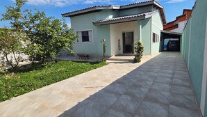 Une maison avec un patio carrelé, un petit jardin et une voiture garée dans l’allée.