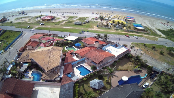 Une station balnéaire comprenant plusieurs bâtiments, une piscine et une plage aménagée avec des parasols.