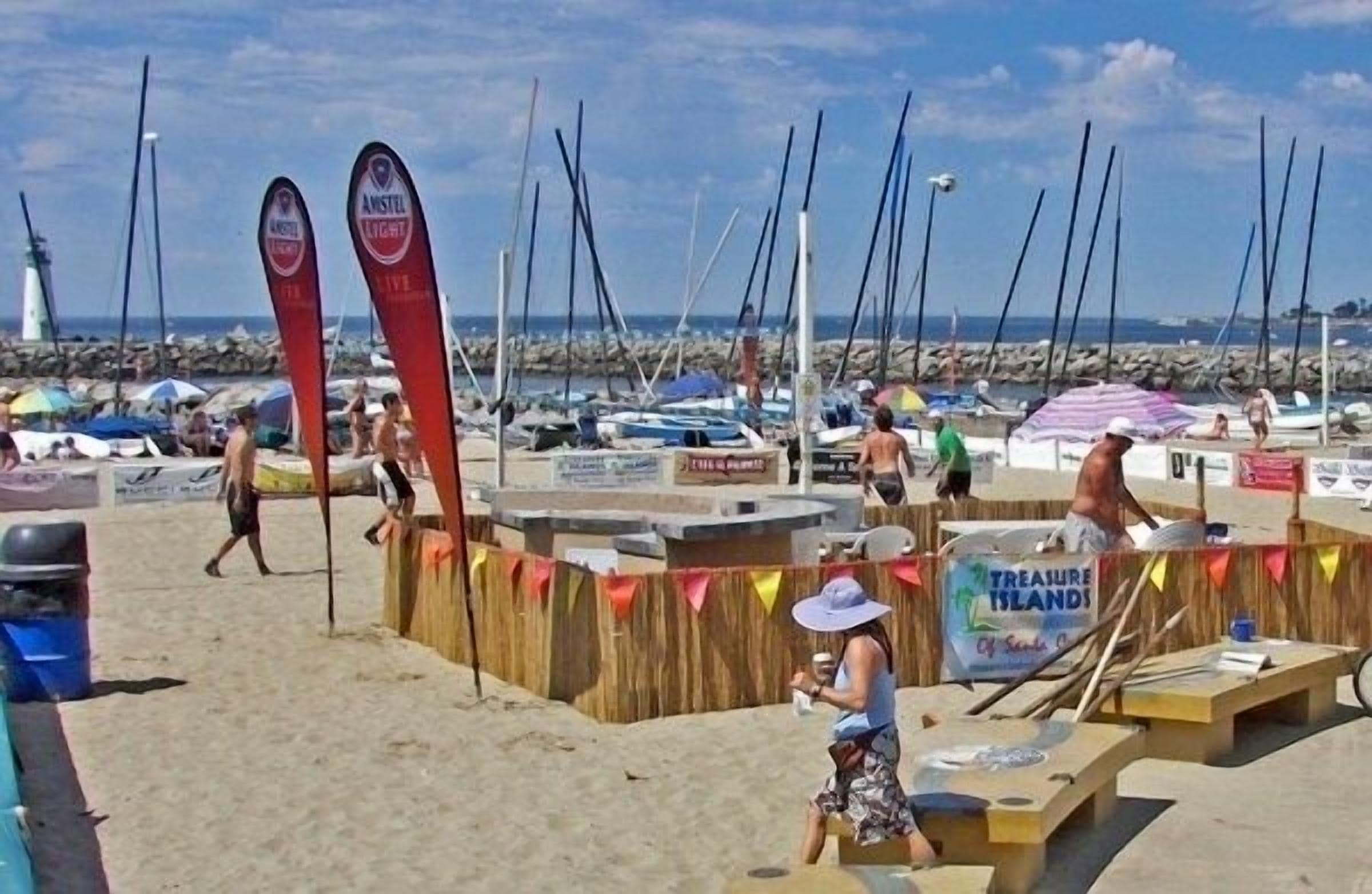 A beach with a wooden structure, a sign for 'Treasure Islands', and several boats in the background.