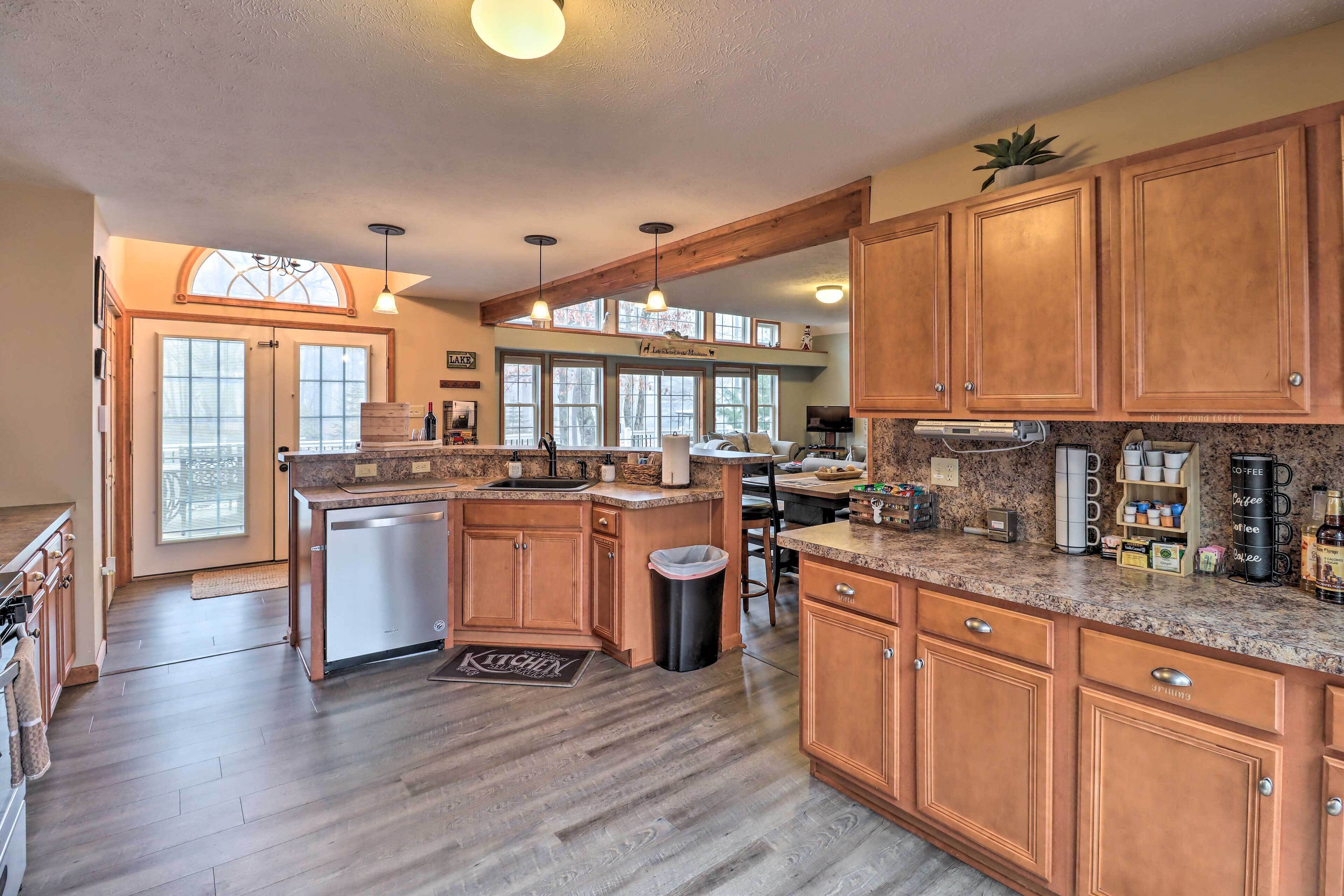 A spacious kitchen with wooden cabinets, a built-in dishwasher, and a large island with a sink.