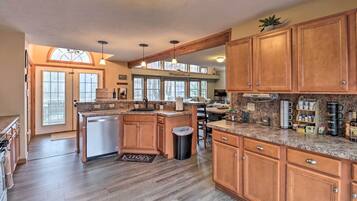 A spacious kitchen with wooden cabinets, a built-in dishwasher, and a large island with a sink.