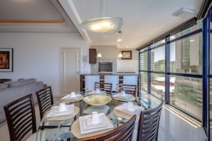 A modern dining area with a glass table, wooden chairs, and a large bowl centerpiece.