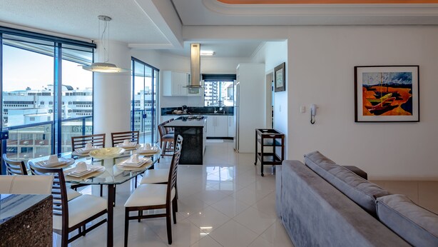 A modern kitchen with a central island, large windows, and a dining area with a glass table. - VERY TOP! Beautiful APARTMENT Ocean Front HIGH STANDARD (Meia Praia)