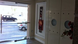 A hotel lobby with a glass door leading outside, a wall-mounted clock, and a decorative wall panel. - VERY TOP! Beautiful APARTMENT Ocean Front HIGH STANDARD (Meia Praia)