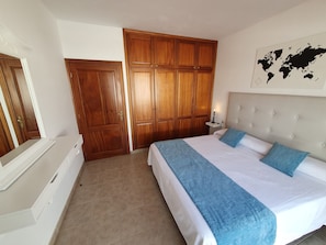 Une chambre à coucher avec un lit, une table de chevet, une carte du monde accrochée au mur et des armoires en bois.